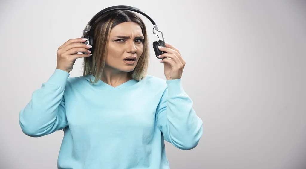 Woman struggling to hear ambient sounds while wearing over-ear headphones