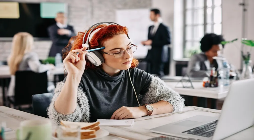 Woman wearing headphones while working in a busy office