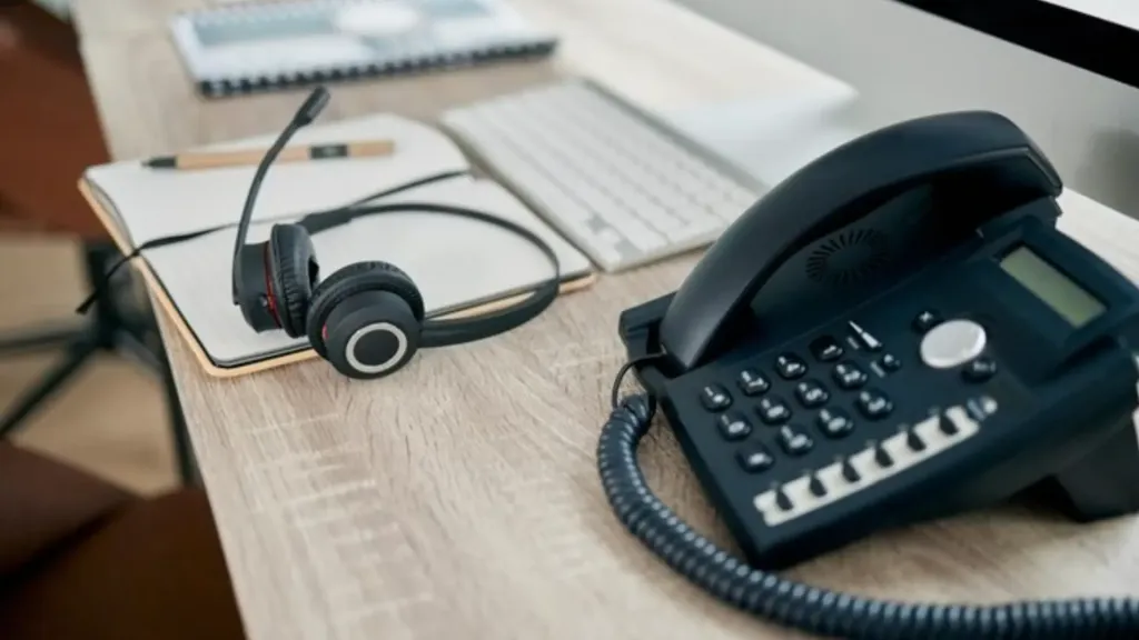 A desk setup with an IP phone headset placed neatly beside an office desk phone, ready for business calls.