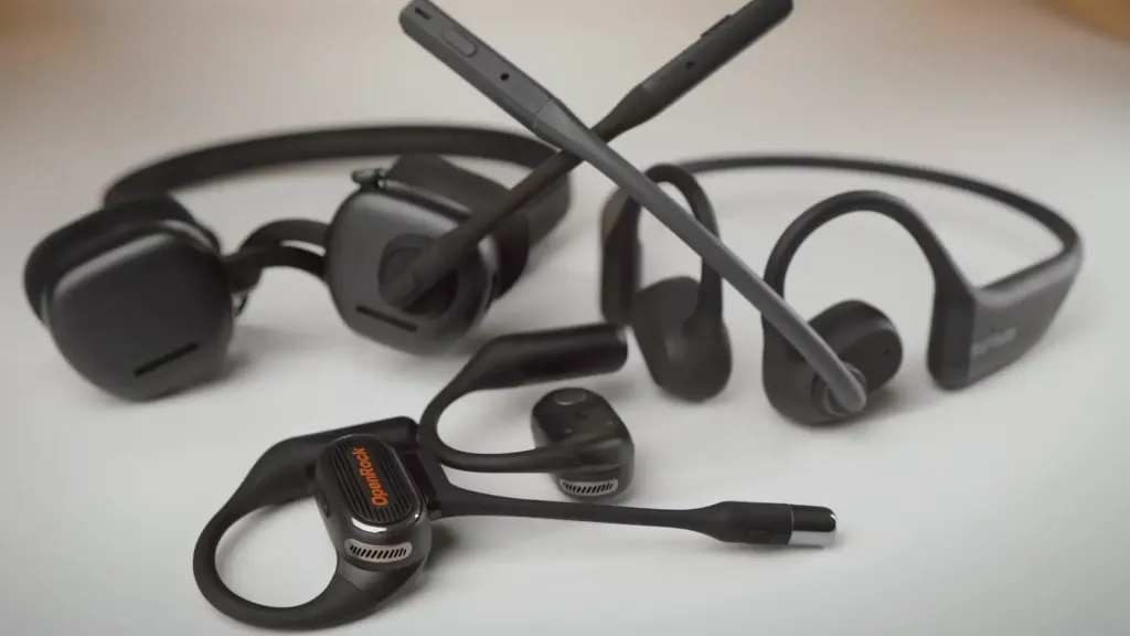 Andy testing the microphones of Nuroum OpenEar Pro 2, Shokz Open Meet, and OpenRock Link 20 open-ear headsets side by side, comparing vocal clarity, AI noise cancellation, and call performance