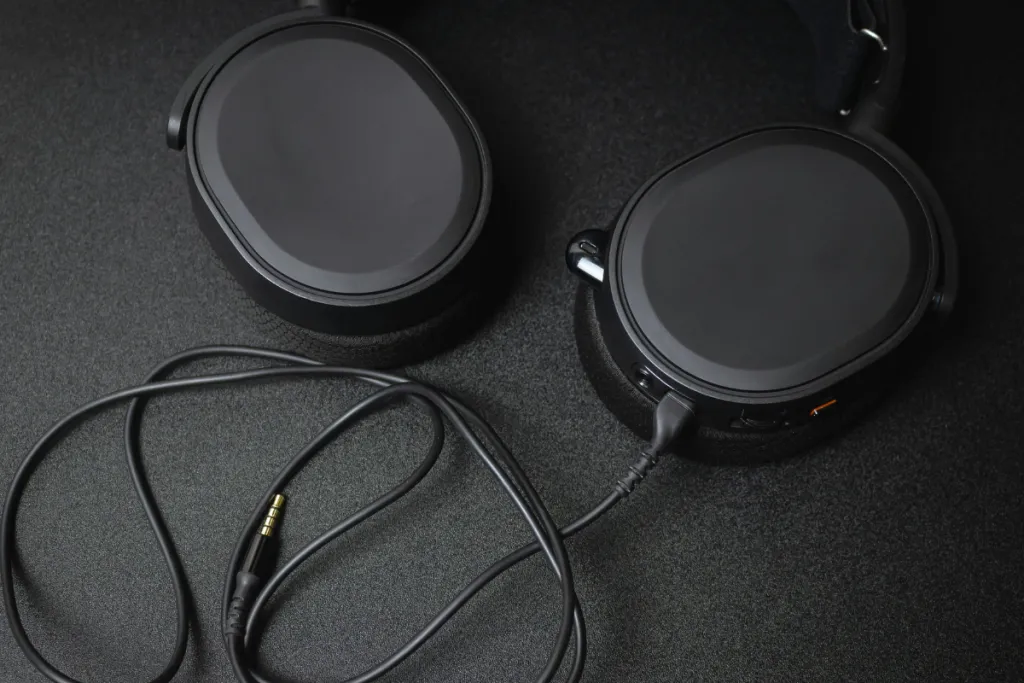 Top-down close-up view of black over-ear headphones with a detachable 3.5mm audio cable on a dark textured surface.