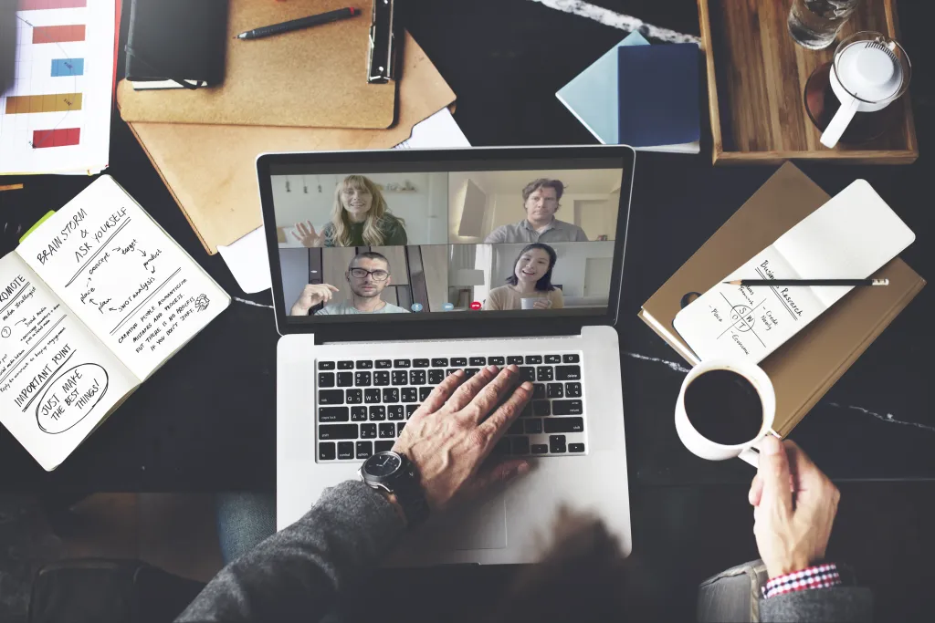 Top-down view of a professional desk setup during an online video conference call, emphasizing the need for a reliable business wireless headset.