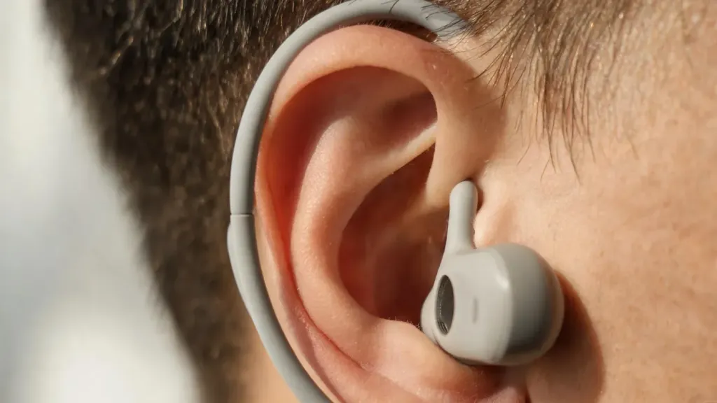 Close-up of an open-ear headset hook resting outside the ear, leaving the ear canal open and free