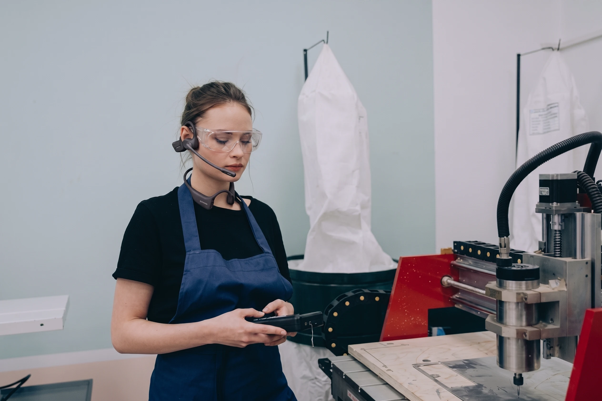 CNC operator wearing open ear headset on manufacturing floor