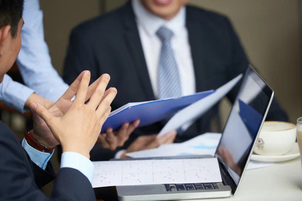 Close-up of legal professionals analyzing case documents and data charts during a client intake meeting.