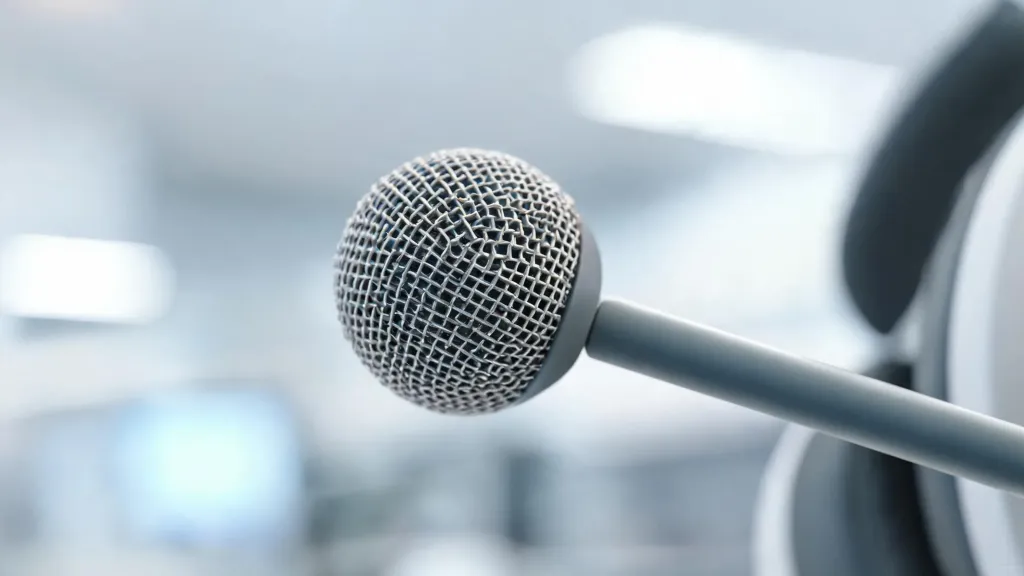Extreme close-up of a headset boom microphone showing the fine mesh grille and small capsule