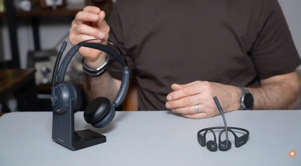 Nuroum HP31D and OpenEar Pro 2 wireless headset with mic displayed on a desk as Tim sits behind them during a headset comparison review for work use