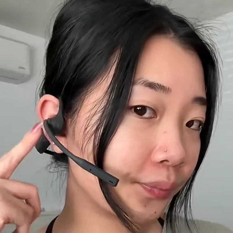 Close-up side view of a woman wearing the Nuroum OpenEar Pro 2 wireless headset with a boom microphone positioned near her mouth.