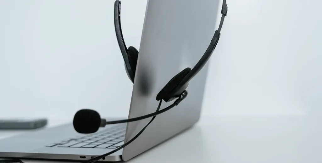 Black office headset with foam ear cushions and boom microphone resting over the display of an open laptop