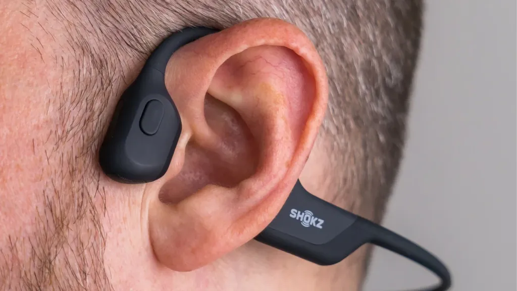 Close-up of a man wearing black Shokz open-ear bone conduction headphones.