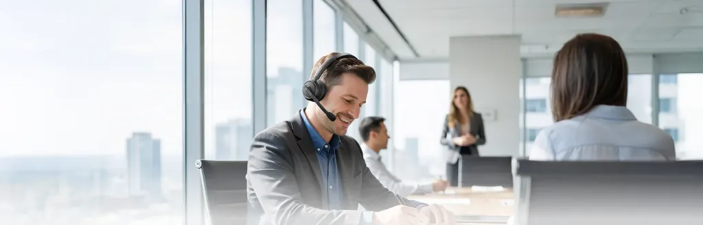 A business professional wearing a single-ear headset with a microphone in a bright corporate office, showcasing an alternative to the best noise cancelling headphones for coding.