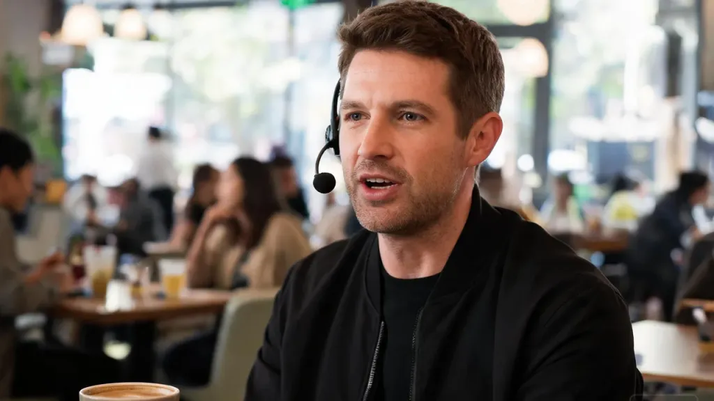 A person wearing a headset and speaking on a call in a busy café, focused amid the background activity