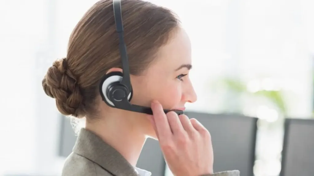 Female professional wearing a VoIP headset during an online business call in a modern office workspace